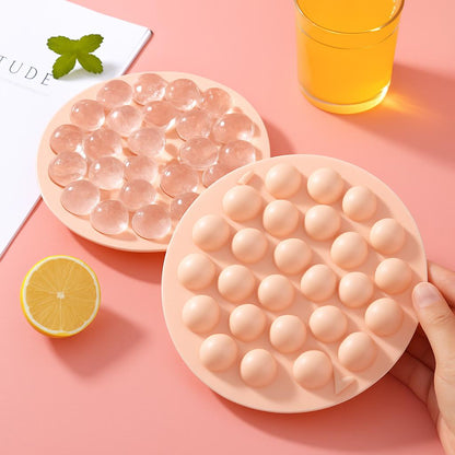 Circular silicone ice cube tray in light pink with dome-shaped compartments